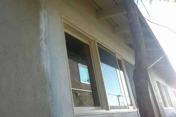 Close-up of a stucco wall with a visible patch around a window on a residential building exterior. — Novato area