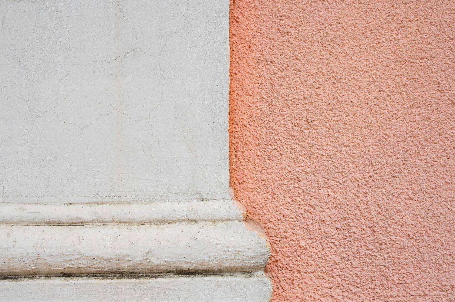 Close-up of stucco wall with smooth light and rough pink textures side by side.