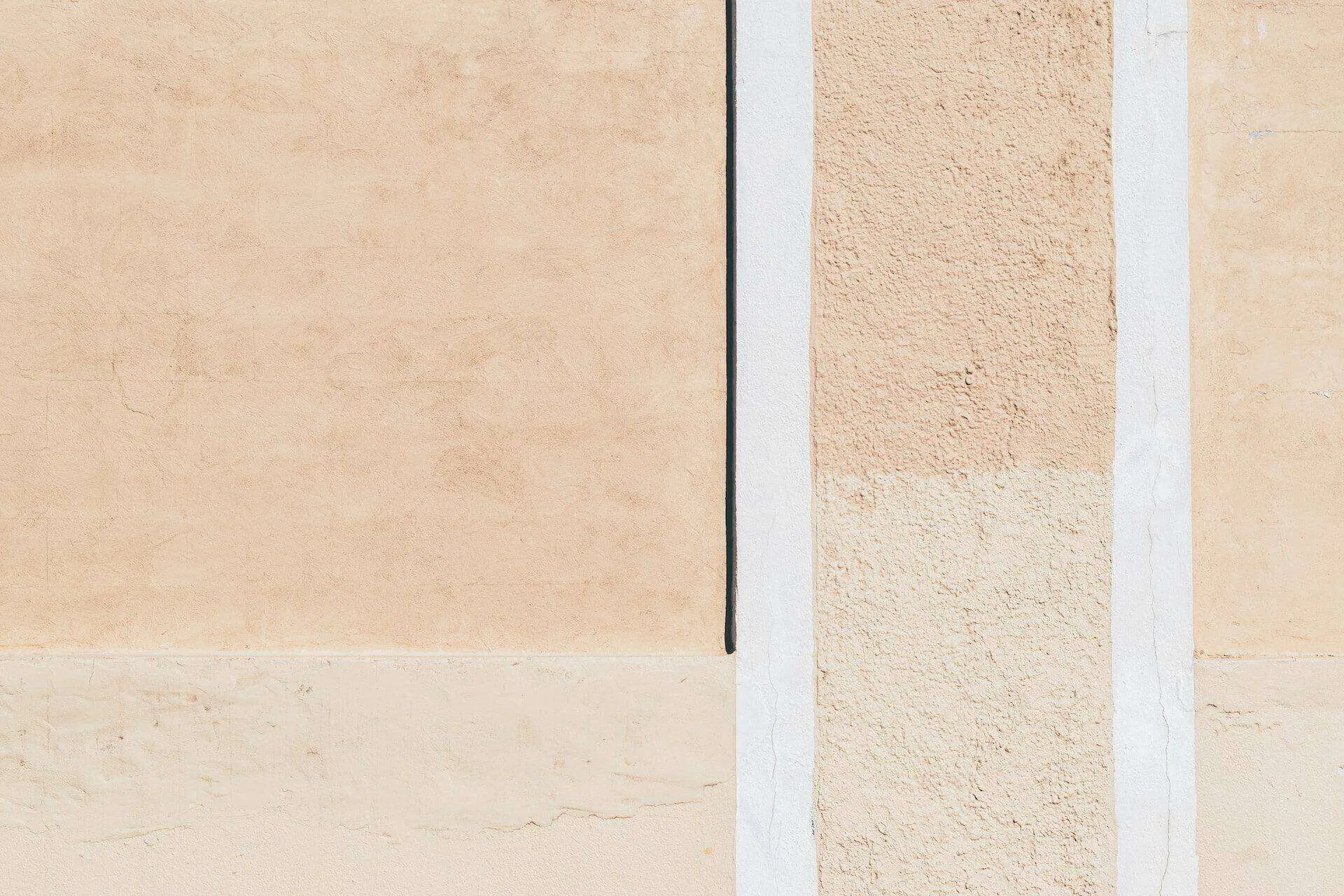 Close-up of a stucco wall with varying textures and beige tones, featuring a vertical seam.