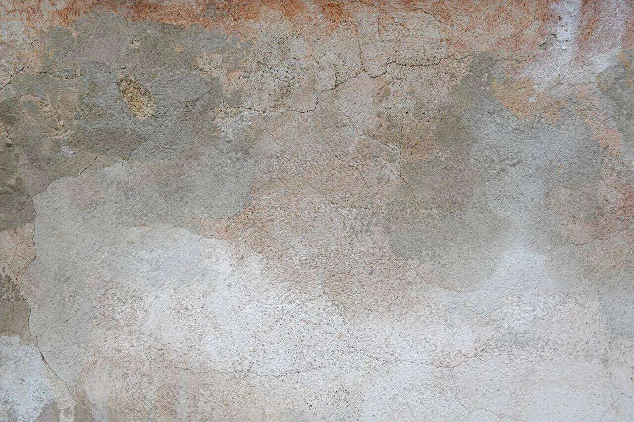 Close-up of a stucco wall showing water damage, cracks, and discoloration. — Kensington area