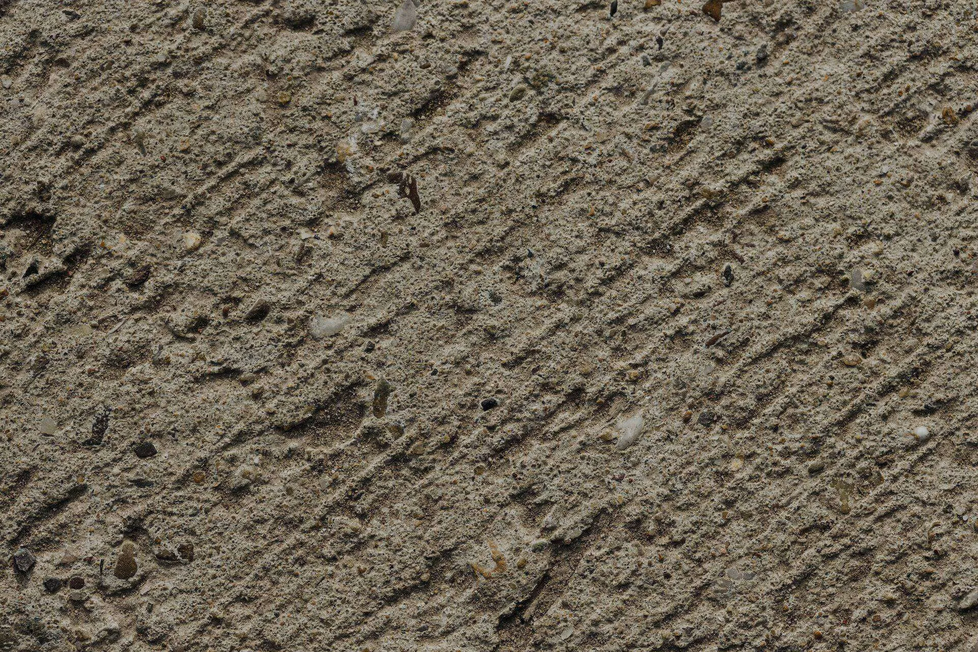 Close-up of a textured concrete surface with visible aggregate and diagonal lines. — Ross area