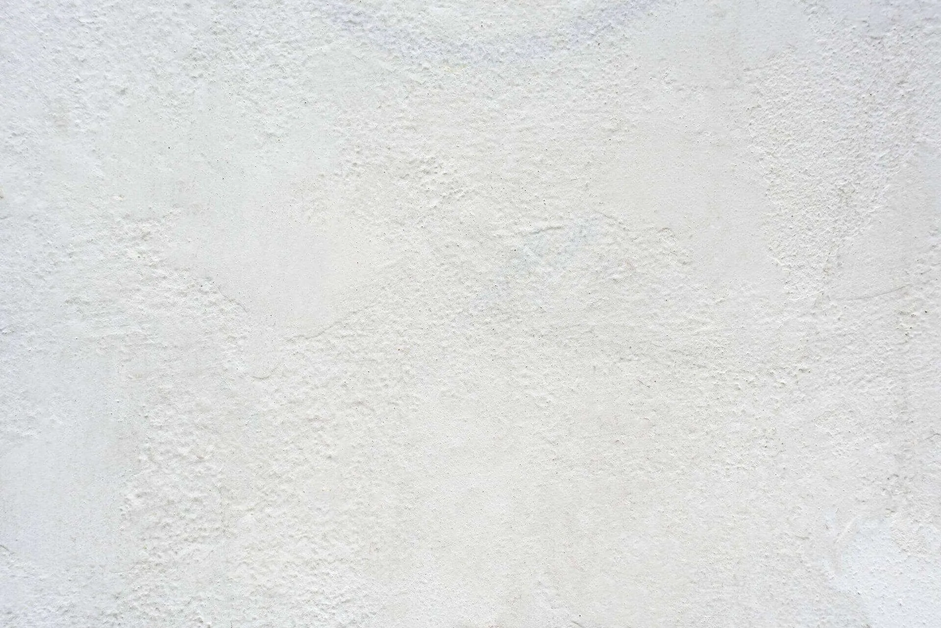 Close-up of a textured plaster wall with a rough finish in a light color.