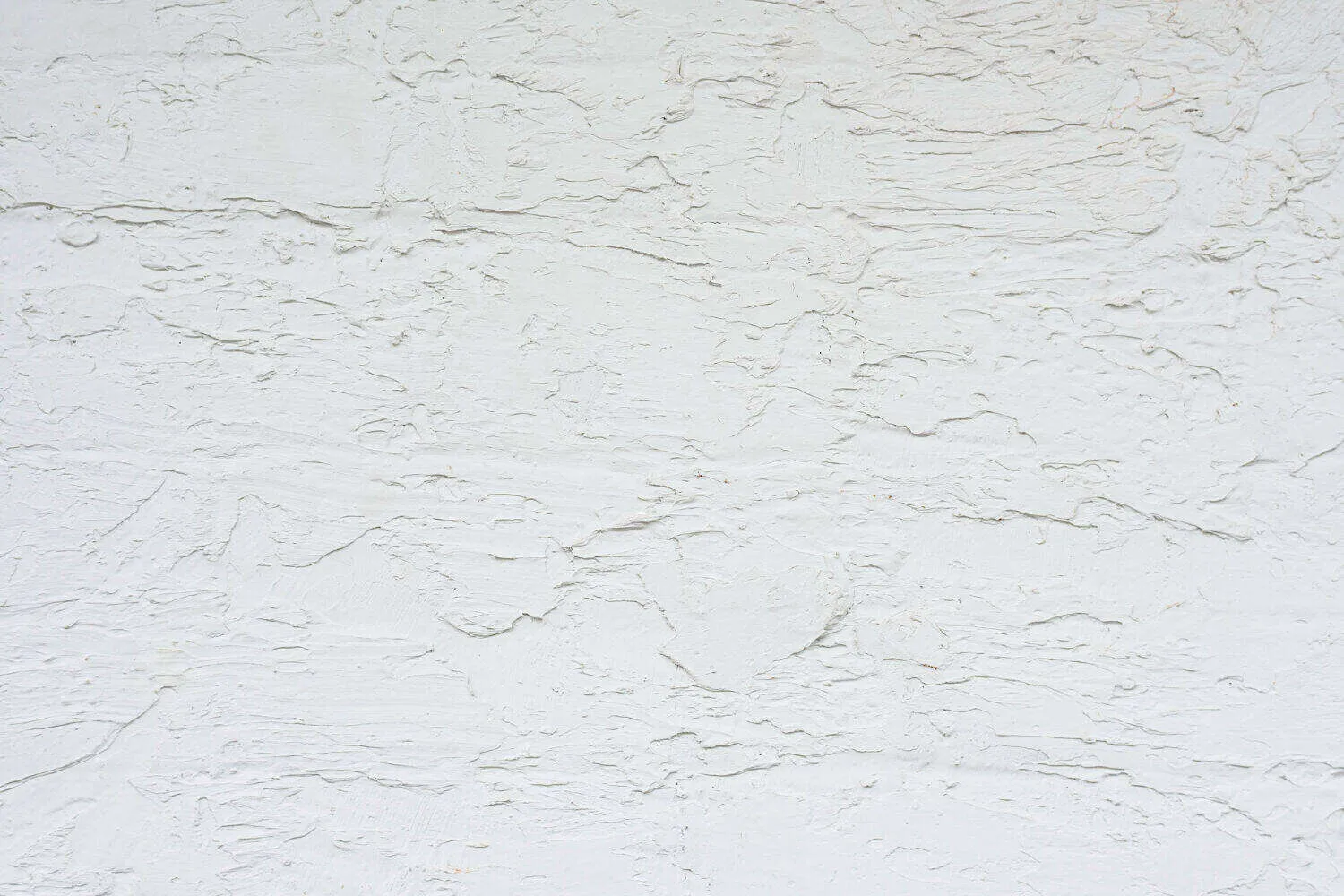 Close-up view of a white textured plaster wall with a rough surface.