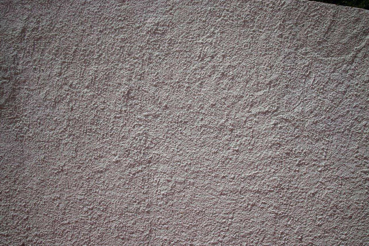 Close-up of a textured stucco wall with a rough, uneven surface.