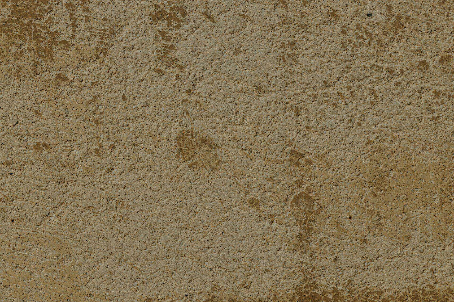 Close-up of a textured stucco wall with a rough finish in brown and beige tones.