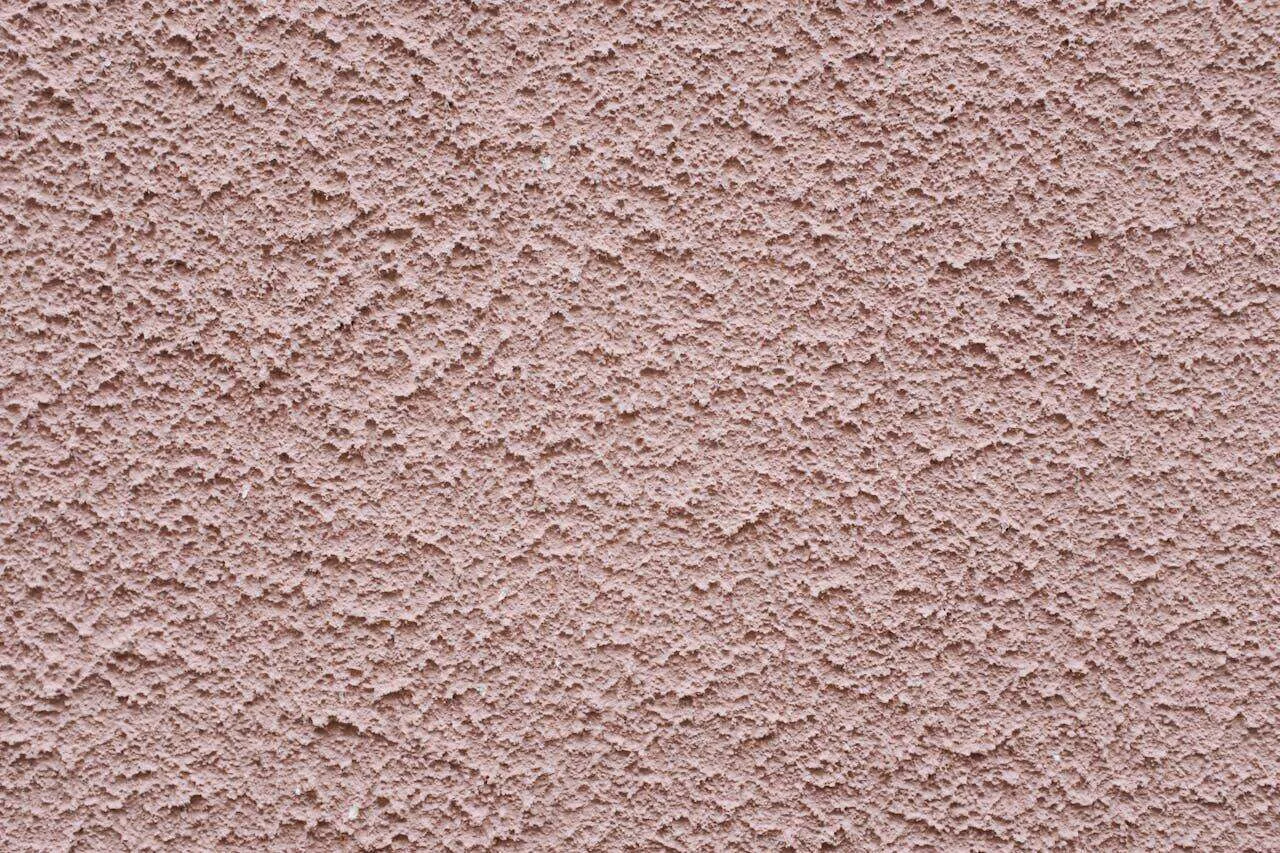 Close-up of a textured stucco wall with a rough finish, showing detail and uniformity.