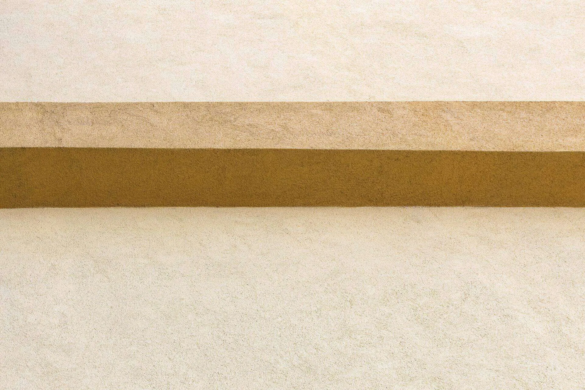 Close-up of a textured wall with two horizontal bands in beige and brown shades.
