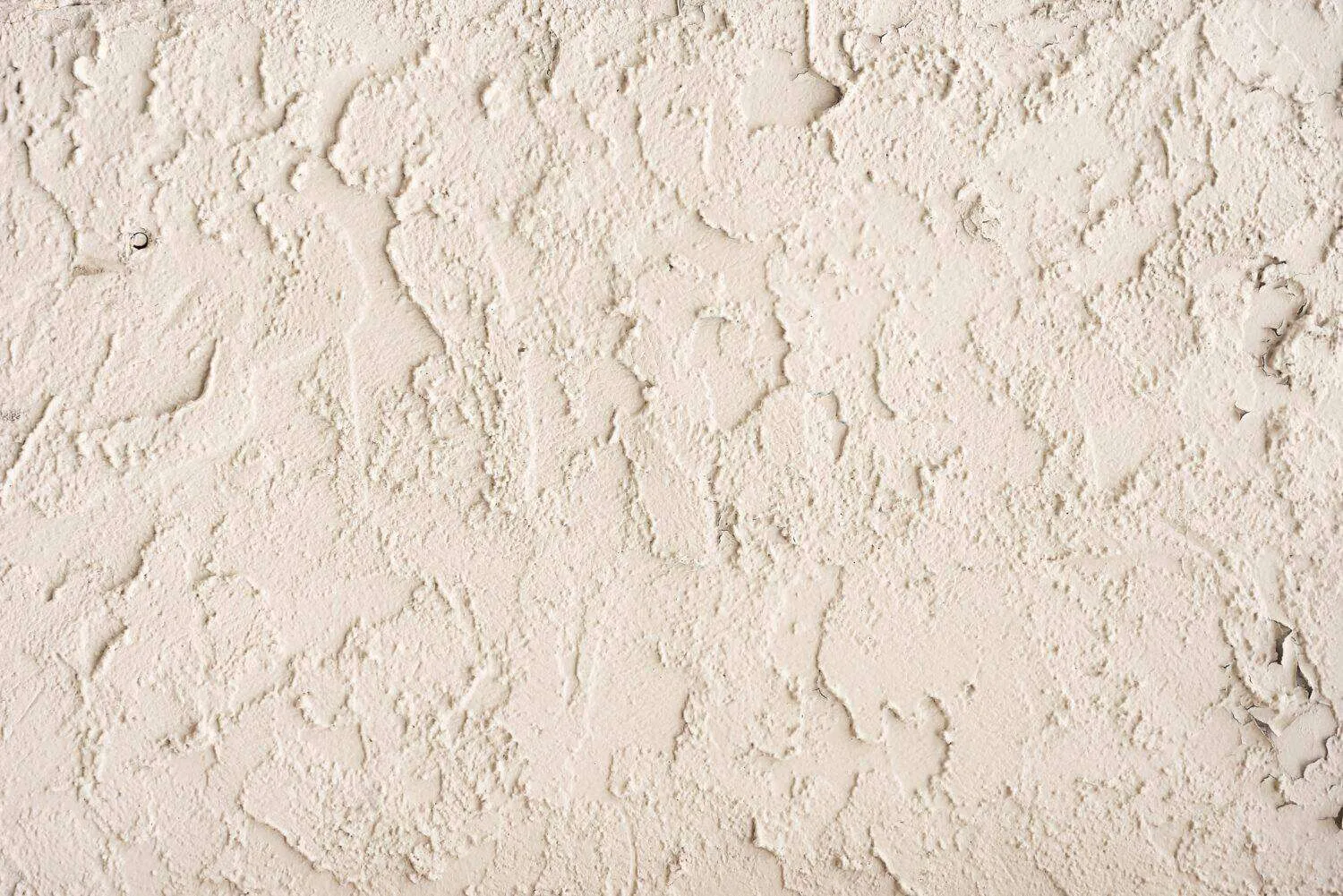 Close-up of a textured white concrete wall with rough finish and irregular patterns.