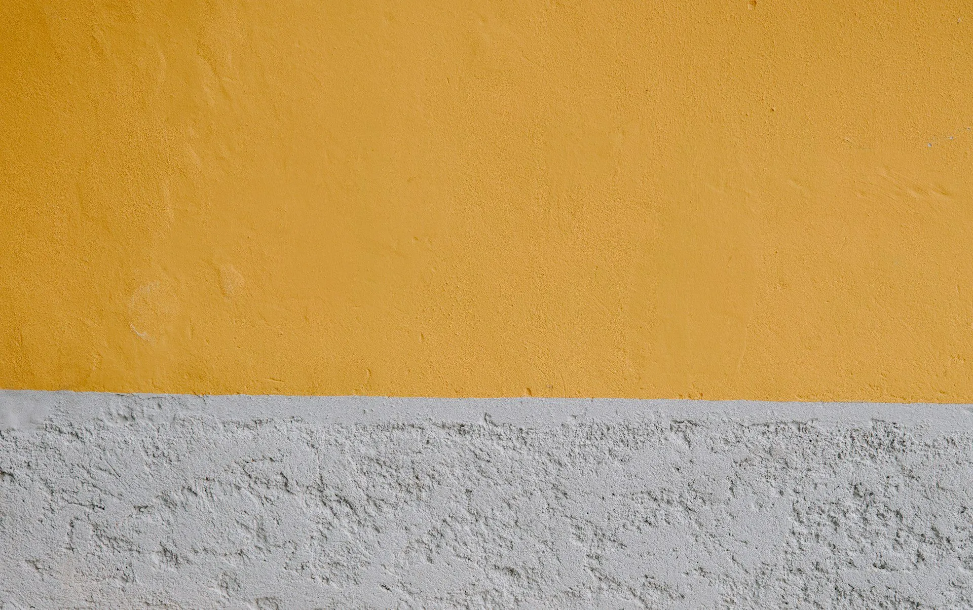 Two-tone plaster wall with smooth yellow and rough gray sections.