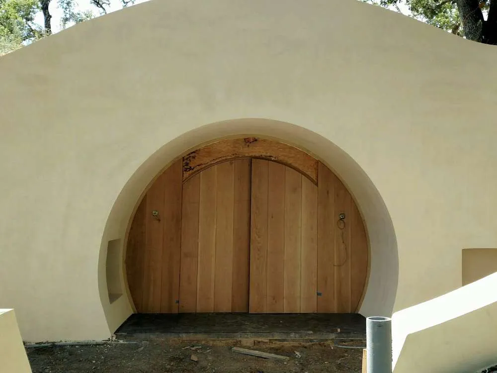 Entrance to an underground wine cave with a wooden door and smooth stucco facade in an outdoor setting. — work near Berkeley
