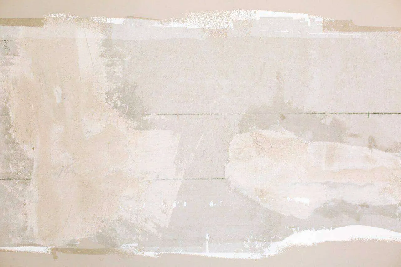Close-up of a wall with partially applied plaster, showing smooth and rough textures.