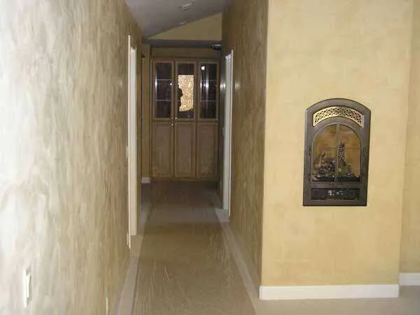 Hallway with Venetian plaster walls and a decorative wall inset, leading to a cabinet.