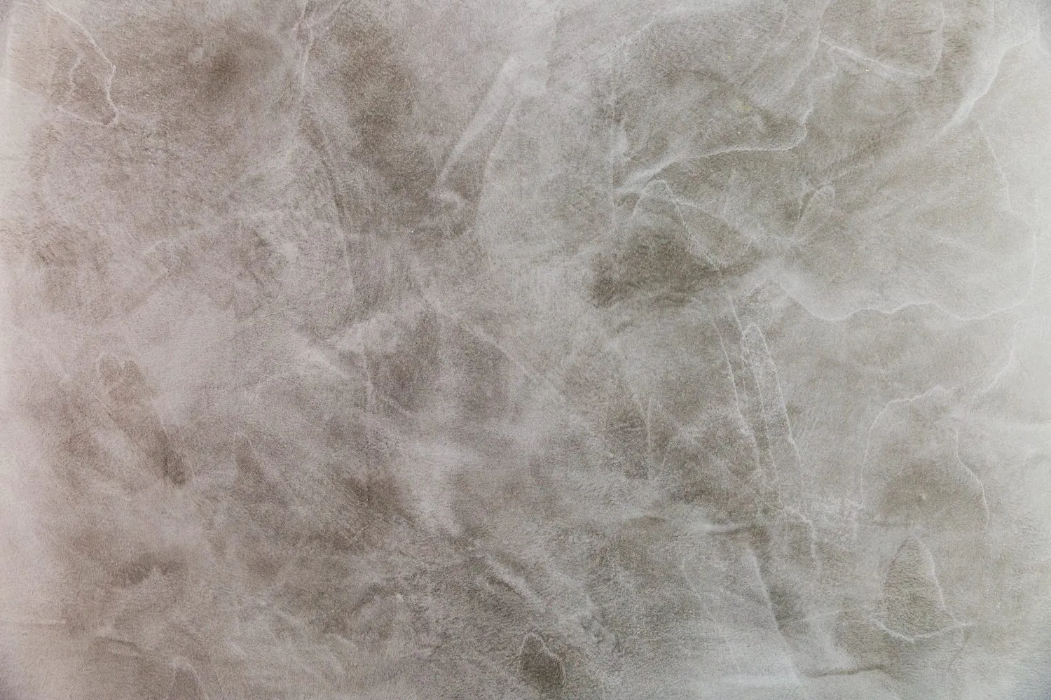 Close-up of a textured wall with a smooth, marbled Venetian plaster finish.