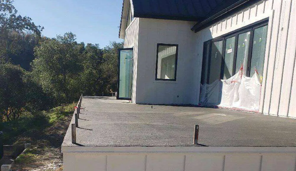 Large deck with waterproof membrane ready for tile installation, attached to a modern building.