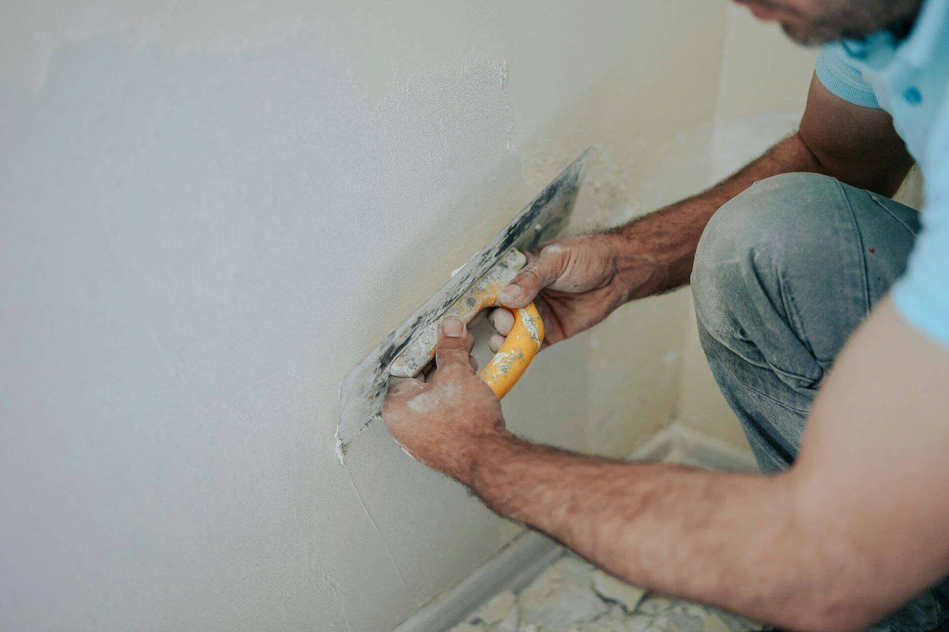 Person applying plaster to a wall with a trowel, focusing on repair or waterproofing.