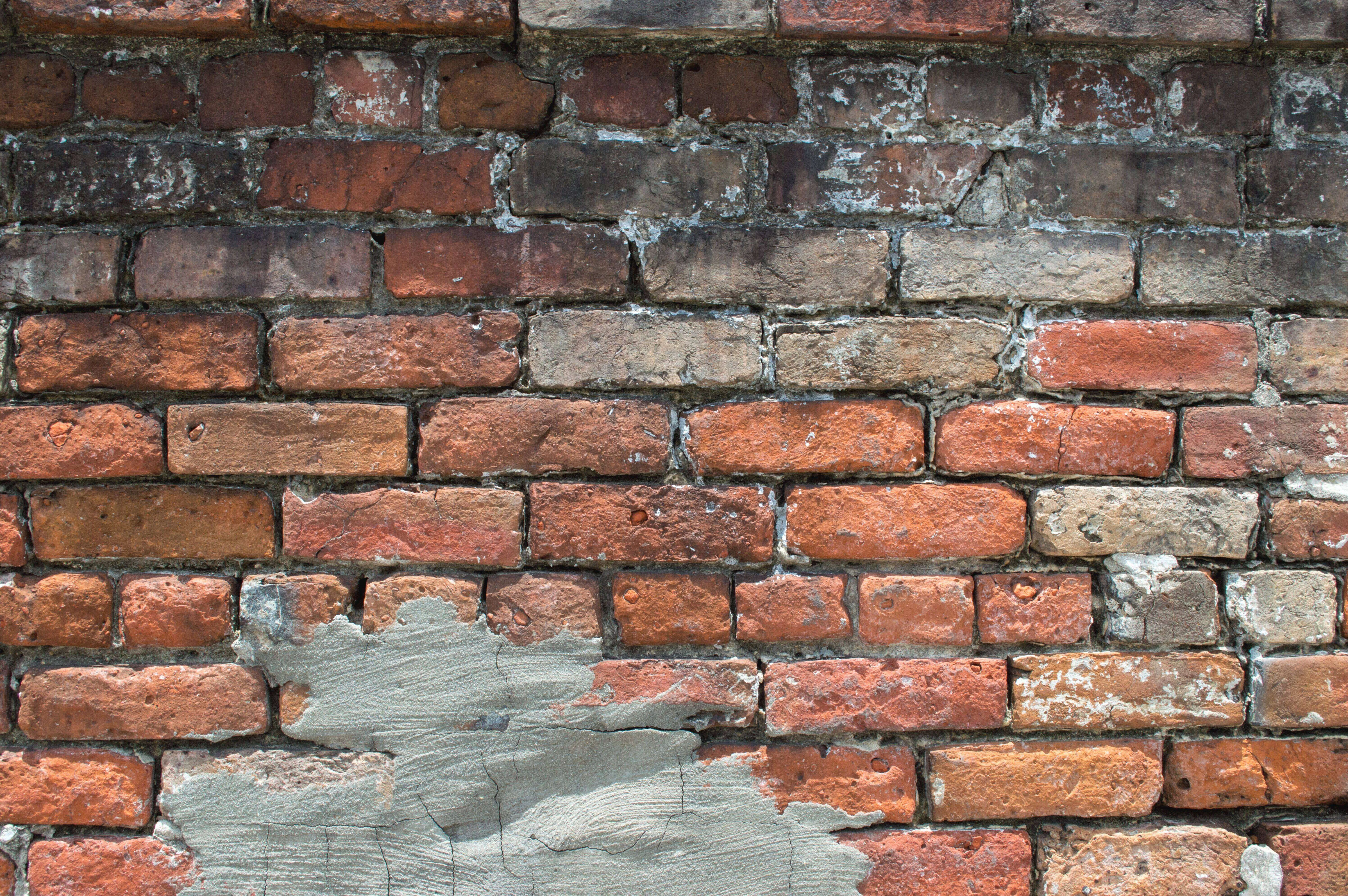 Weathered brick wall with patches of gray plaster, showing signs of aging and wear.