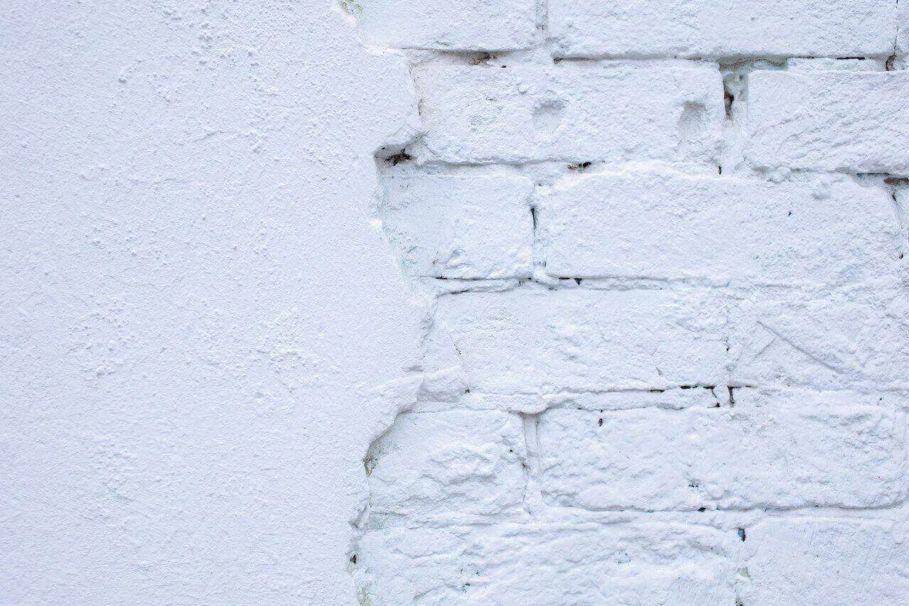 White painted brick wall with partially exposed plaster revealing bricks underneath. — Berkeley area