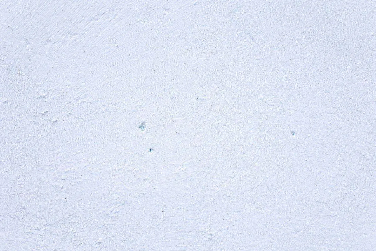 Close-up of a white textured plaster wall with subtle imperfections.
