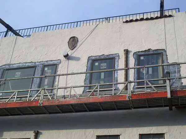 Building facade with three windows being patched, scaffolding in place.
