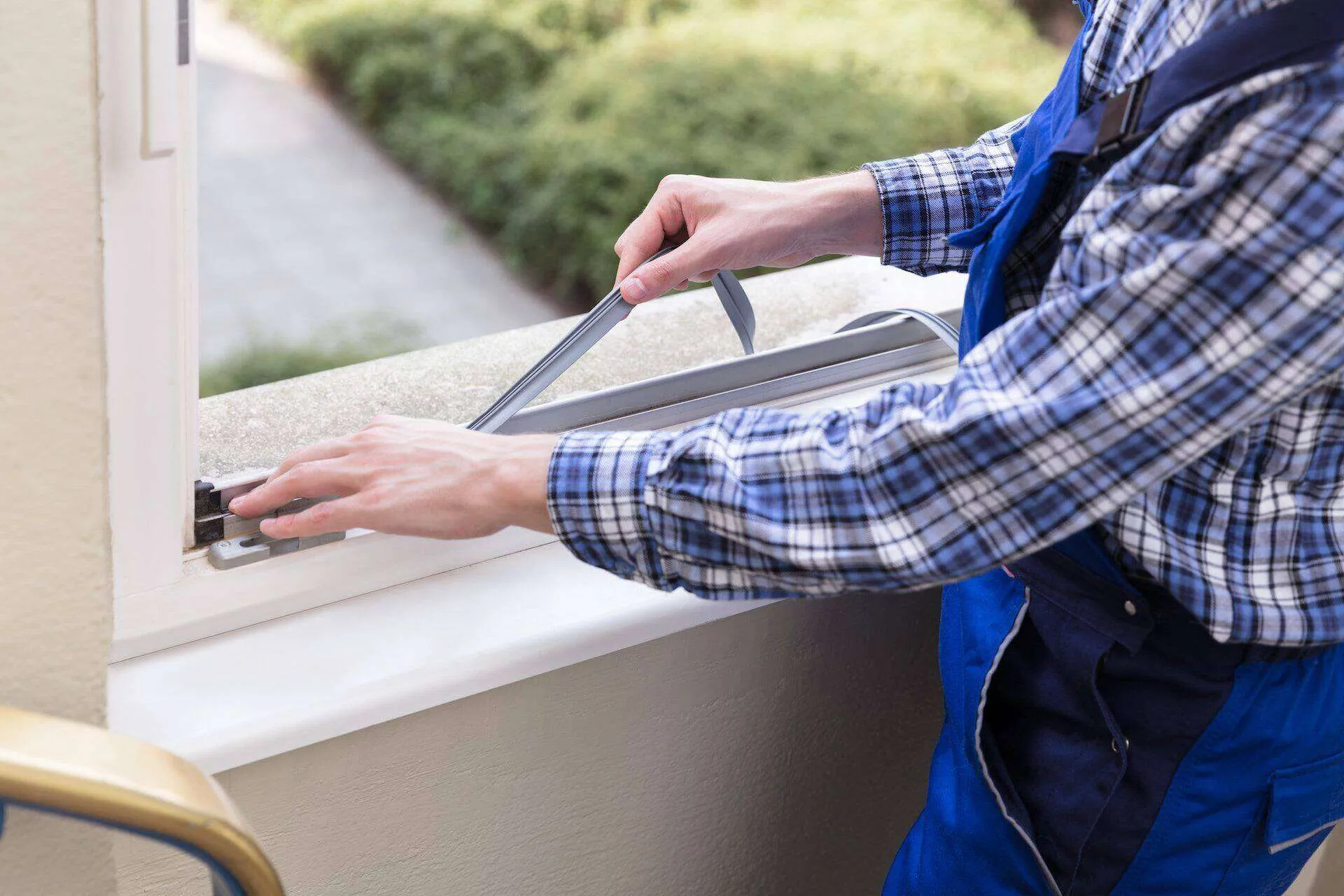 Person installing weather stripping on a window frame, enhancing waterproofing.