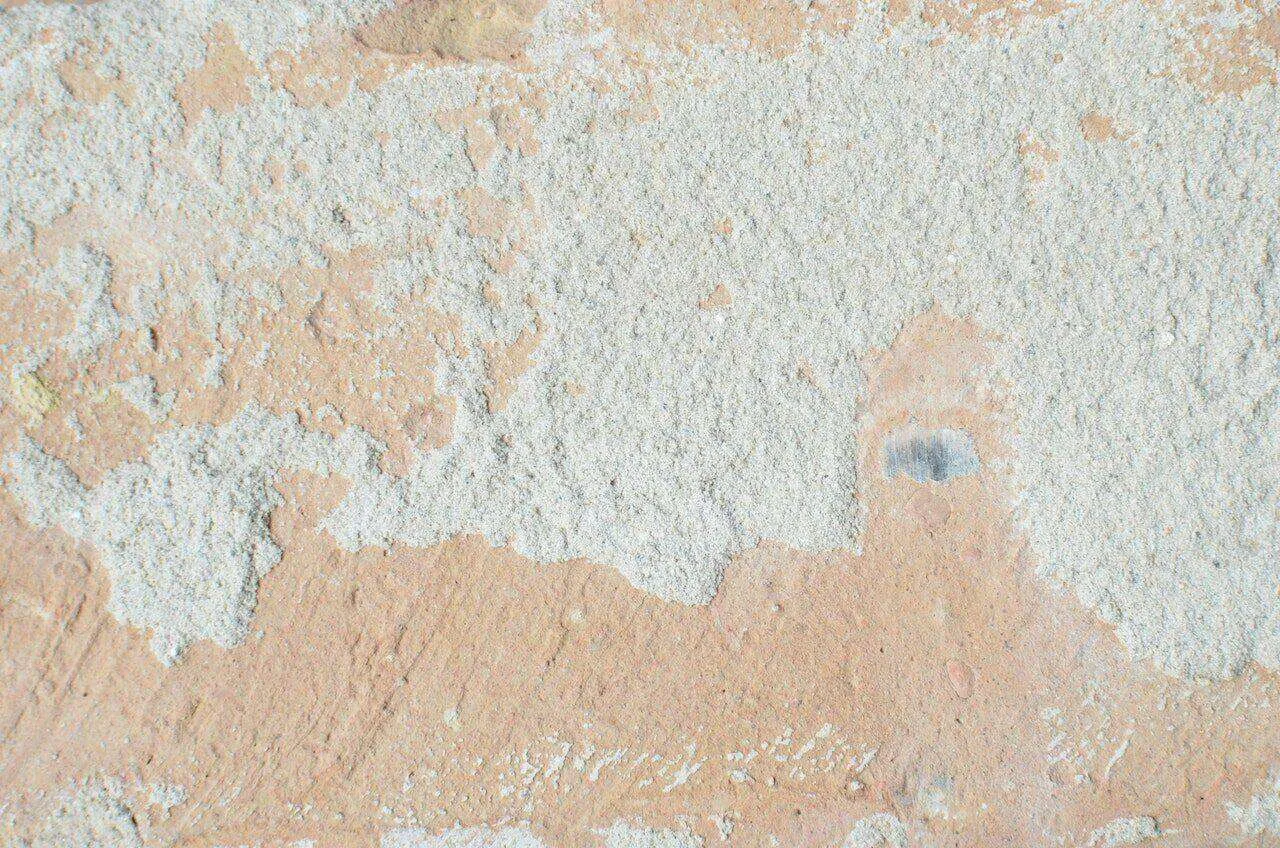 Close-up of a worn stucco wall with peeling and rough texture.
